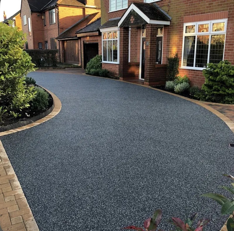 Charcoal resin bound driveway edged with golden block paving on a curved frontage