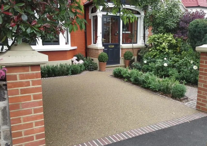 Golden resin bound front driveway with clay paver border and red-brick garden wall on a period home